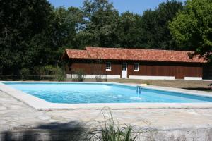 einen Pool vor einer Scheune und einem Gebäude in der Unterkunft Gite en forêt landaise avec jacuzzi d'intérieur in Pissos