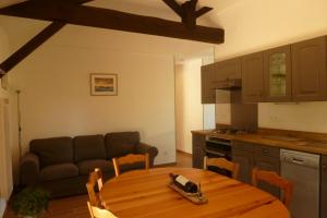 eine Küche mit einem Holztisch und einem Sofa in der Unterkunft Gite en forêt landaise avec jacuzzi d'intérieur in Pissos