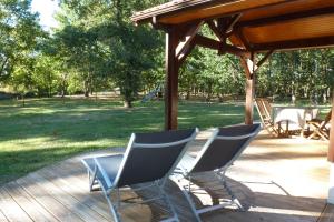 zwei Stühle auf einem Deck unter einem Pavillon in der Unterkunft Gite en forêt landaise avec jacuzzi d'intérieur in Pissos