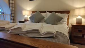 a bed with white sheets and pillows and two lamps at 1 Chapel Nazareth in Penrhyndeudreath