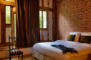 1 dormitorio con 1 cama con pared de ladrillo en Golf de Rebetz- Domaine de Rebetz, en Chaumont-en-Vexin