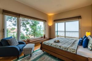 a bedroom with a bed and a couch and windows at StayVista at Ludlow House Luxury 4BHK Valley View villa in Kasauli with Sauna room in Kasauli