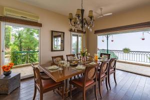 a dining room with a table and chairs and windows at StayVista at Ludlow House Luxury 4BHK Valley View villa in Kasauli with Sauna room in Kasauli