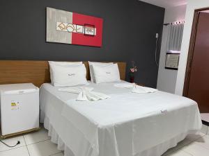 a large white bed with white sheets and pillows at Hotel Rota do Sertão in Serra Talhada +15 photos