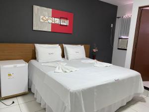 a large white bed with white sheets and pillows at Hotel Rota do Sertão in Serra Talhada