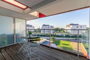 d'un balcon avec une table, des chaises et une grande fenêtre. dans l'établissement OVELIA Strasbourg - Les Jardins des Deux Rives, à Strasbourg