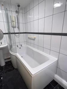 a white bath tub in a bathroom with a sink at Forge Cottage in Mountain Ash