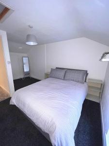 ein Schlafzimmer mit einem großen weißen Bett in einem Zimmer in der Unterkunft Forge Cottage in Mountain Ash