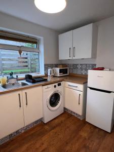 a kitchen with white cabinets and a washer and dryer at Forge Cottage in Mountain Ash