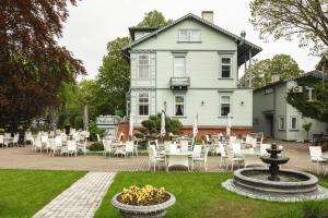 a patio with tables and chairs in front of a house at Roze Boutique Hotel in Liepāja
