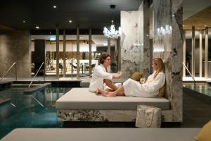 un hombre y una mujer sentados en una cama en una piscina en Hotel Vinifera Wine & Spa 5 Stars Superior, en Balatonfüred