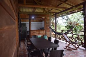 eine Terrasse mit einem Tisch, Stühlen und einer Hängematte in der Unterkunft Casa Campestre Reina María in San José del Guaviare