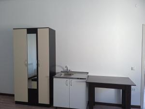 uma cozinha com um lavatório, uma mesa e um espelho em Частый дом em Kapchagay
