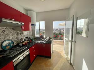 a kitchen with red cabinets and a stove top oven at Terrasse En Vue in Temara