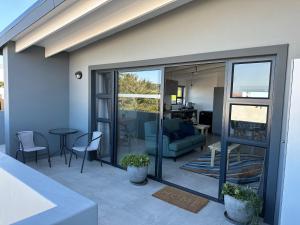 a living room with a patio with a table and chairs at Modern apartments downtown in Plettenberg Bay