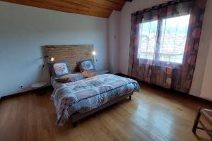 ein Schlafzimmer mit einem Bett und einem großen Fenster in der Unterkunft La Maison des 3 Bouleaux 