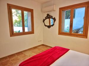 una camera da letto con una coperta rossa su un letto con finestre di VILLA SOFIA a Valldemossa