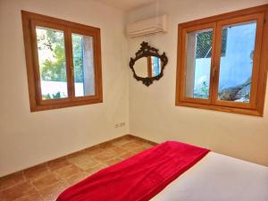 a bedroom with a red blanket on a bed with windows at VILLA SOFIA in Valldemossa