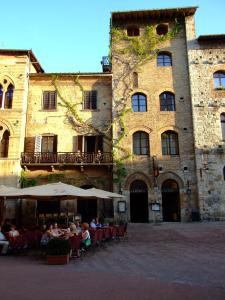 un grupo de personas sentadas en mesas frente a un edificio en Hotel La Cisterna, en San Gimignano