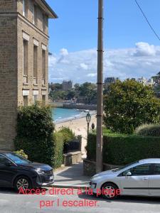 a view of a beach with cars parked on a street at Appartement 40m2 vue sur mer accès direct plage et parking privé in Dinard