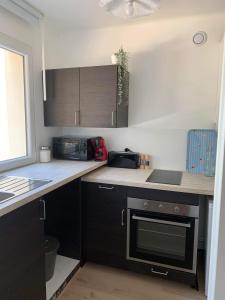 a kitchen with black cabinets and a stove top oven at Appartement 40m2 vue sur mer accès direct plage et parking privé in Dinard