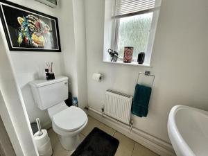 a bathroom with a toilet and a sink and a window at Tailor That Property - High Street in Northampton