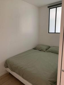 Cama en habitación blanca con ventana en Appartement 40m2 vue sur mer accès direct plage et parking privé, en Dinard
