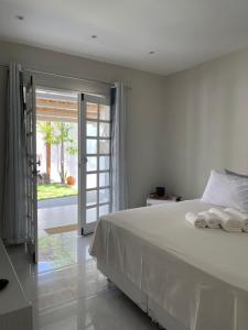 a bedroom with a white bed and a sliding glass door at Charlotte House in Canoa Quebrada