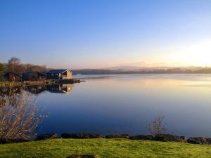 a view of a lake with a house on the shore at Pine Lake Resort in Carnforth