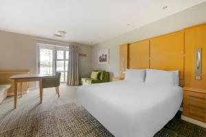 een slaapkamer met een groot wit bed en een bureau bij Pine Lake Resort in Carnforth