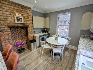 a kitchen with a table and a brick wall at Robert Bolt House, Free Parking, 1 Minute to Metrolink in Sale