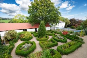 um jardim com sebes aparadas em frente a um edifício em Ballyknocken Milking Parlour Self Catering Apartment em Coolnakilly