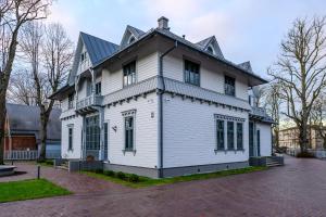 een wit huis met een gambrel dak bij Roze Peldu Residence in Liepāja