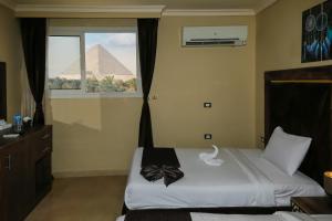a bedroom with a bed with the pyramid in the background at King Cheops Inn - Pyramid View in Cairo