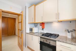 a kitchen with white cabinets and a stove top oven at Vilamoura Marina in Vilamoura