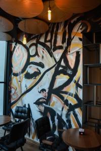 a wall covered in graffiti in a room with tables and chairs at BAZ'HUR Boutique Hotel in Kukës