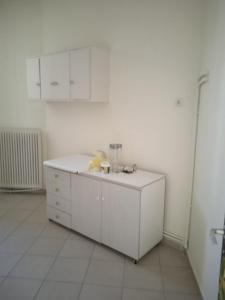 a white kitchen with a teddy bear sitting on a cabinet at COMFORT RENT in Lamía