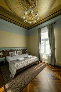 a bedroom with a bed and a ceiling with a chandelier at Roze Peldu Residence in Liepāja