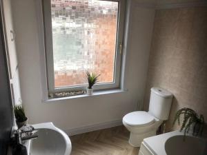 a bathroom with a toilet and a sink and a window at 15 Comfort House 2 bed townhouse with parking in Scunthorpe