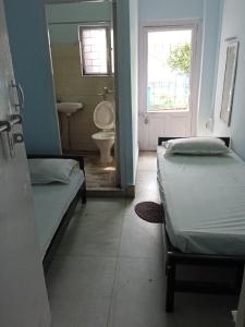 a room with two beds and a bathroom with a sink at Centerpoint Guest House in Kolkata