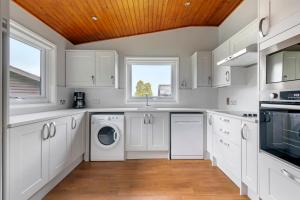 uma cozinha com armários brancos e uma máquina de lavar e secar roupa em Pine Lake Resort em Carnforth