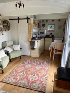a kitchen and living room with a rug and a table at Muffins Meadow Shepherds Hut in Tillingham
