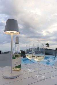 ヴィアグランデにあるViscalori Homesのテーブルの上には白ワインのグラス2つとランプが置かれている