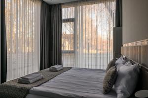 een slaapkamer met een groot bed en 2 grote ramen bij Roze Peldu Residence in Liepāja