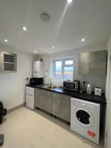 New Bedfont的住宿－Large studio flat B near Heathrow，厨房配有洗衣机、水槽和微波炉
