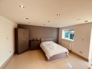 Large studio flat B near Heathrow في New Bedfont: غرفة نوم بسرير وخزانة ونافذة