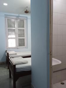 a room with three beds and a sink and a window at Centerpoint Guest House in Kolkata
