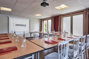 una sala de conferencias con mesas, sillas y una pantalla en The Originals City Hôtel La Verrière-Yvelines, en La Verrière