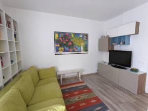 ein Wohnzimmer mit einem grünen Sofa und einem TV in der Unterkunft Casa al mare Piera in Cinquale