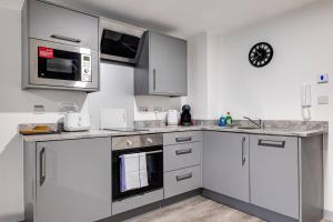 a kitchen with stainless steel appliances and a clock on the wall at Modern & Centrally Located Apartment in Liverpool